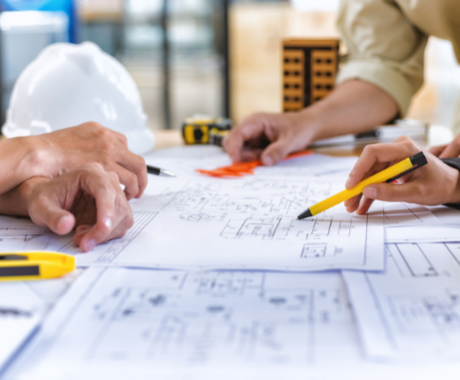 Three people review construction site plans.