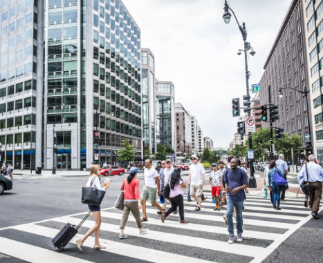 Photo of people crossing a busy street in downtown Washington, DC.